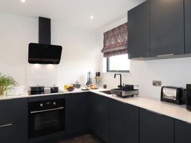 A modern kitchen with black cabinets a stove oven and toaster at Yew Tree Cabin in Ullswater
