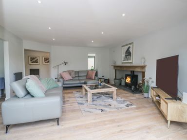 A living room with two grey sofas a wooden coffee table a fireplace and a television at Greystones in Upton St Leonards