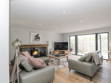 A living room with two grey sofas a wooden coffee table a fireplace and a large television at Greystones in Upton St Leonards