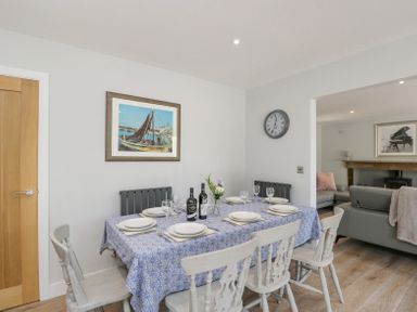 A dining area with a table set for six with plates wine glasses and bottles next to a living room at Greystones in Upton St Leonards