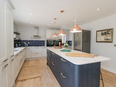 A kitchen with a large island counter and pendant lights at Greystones in Upton St Leonards