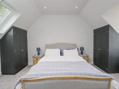 A bedroom with a double bed bedside tables blue lamps and built-in wardrobes at Greystones in Upton St Leonards