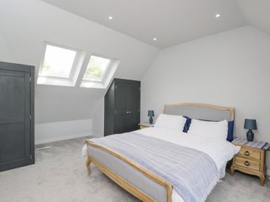 A bedroom with a double bed bedside tables with lamps two black wardrobes and skylight windows at Greystones in Upton St Leonards