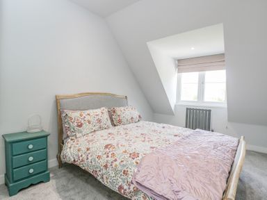 A bedroom with a floral bedspread bed and a teal bedside table at Greystones in Upton St Leonards