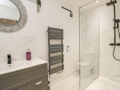A bathroom with a sink vanity unit mirror towel radiator toilet and walk in shower at Greystones in Upton St Leonards