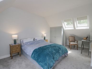 A bedroom with a double bed two bedside tables with lamps a wardrobe a chair and a desk under skylights at Greystones in Upton St Leonards