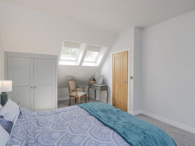 A bedroom with a bed a wooden chair a small desk a wardrobe two skylight windows and a wooden door at Greystones in Upton St Leonards