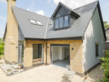 A modern house exterior with stone and brick walls a slate roof and outdoor seating at Greystones in Upton St Leonards