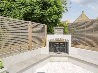 An outdoor seating area with a built-in fireplace and wooden slat fencing at Greystones in Upton St Leonards