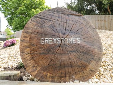 A large wooden log with GREYSTONES written on it outdoors in a garden area with gravel and plants at Greystones in Upton St Leonards