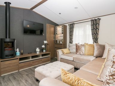 A living room with a beige sectional sofa and patterned curtains at 43 Pony Meadow in Troutbeck Bridge