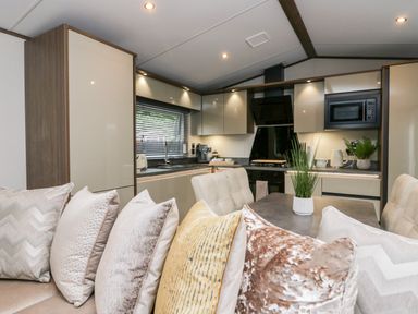 A kitchen and dining area with a sofa featuring multiple pillows and cabinets with appliances at 43 Pony Meadow in Troutbeck Bridge