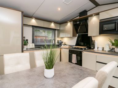 A kitchen with dining table and chairs a stove microwave and cabinets at 43 Pony Meadow in Troutbeck Bridge