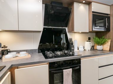 A kitchen countertop with a gas stove oven microwave kettle knives and cups at 43 Pony Meadow in Troutbeck Bridge
