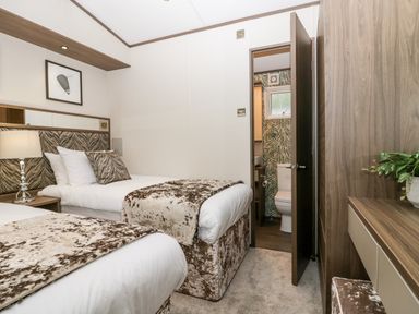 A bedroom with two single beds a bedside table with a lamp a wardrobe and an en suite bathroom at 43 Pony Meadow in Troutbeck Bridge