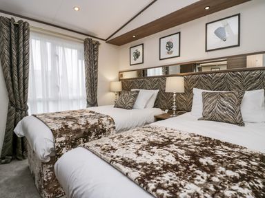 A bedroom with two single beds table lamps and framed pictures above the headboard at 43 Pony Meadow in Troutbeck Bridge