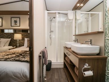 A bathroom with double sinks a shower and a view into a bedroom at 43 Pony Meadow in Troutbeck Bridge