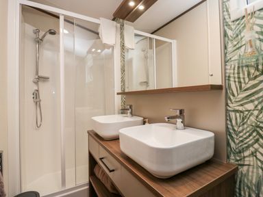 A bathroom with a double sink vanity unit and a glass shower enclosure at 43 Pony Meadow in Troutbeck Bridge