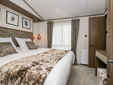 A bedroom with a bed a bedside lamp curtains a door and a dresser at 43 Pony Meadow in Troutbeck Bridge