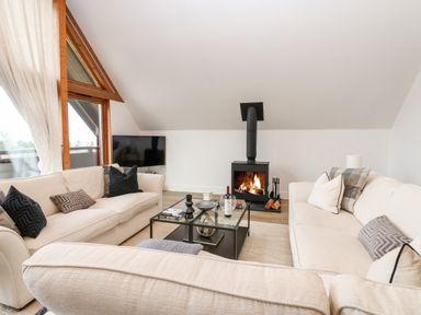 A living room with beige sofas a glass coffee table a fireplace and large windows at Slaley Park Villa in Hexham