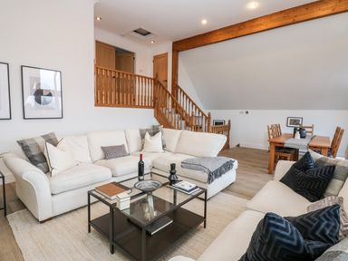 A living room with white sofas a glass coffee table and wooden stairs at Slaley Park Villa in Hexham