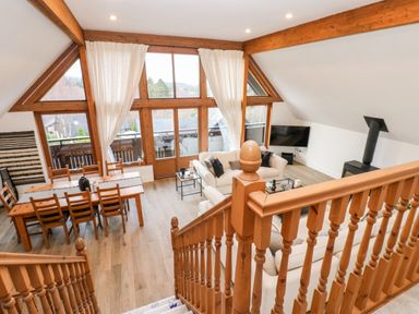 A living room with wooden dining table chairs white sofas large windows and a wood stove at Slaley Park Villa in Hexham
