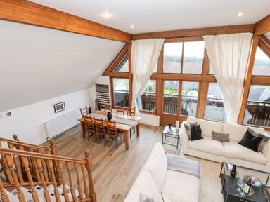 A living room with large windows wooden dining table with chairs and white sofas at Slaley Park Villa Hexham