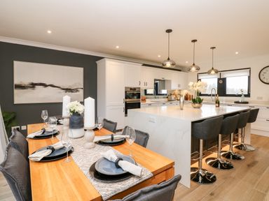 A kitchen and dining area with a wooden dining table set for four and a large kitchen island with four bar stools at Slaley Park Villa in Hexham