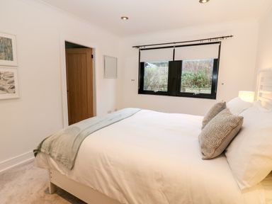 A bedroom with a double bed two pillows a blanket and a window with roller blinds at Slaley Park Villa in Hexham