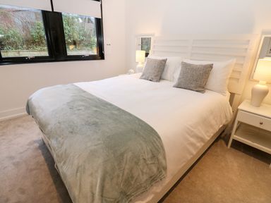A bedroom with a bed two pillows two bedside tables lamps and a window at Slaley Park Villa in Hexham