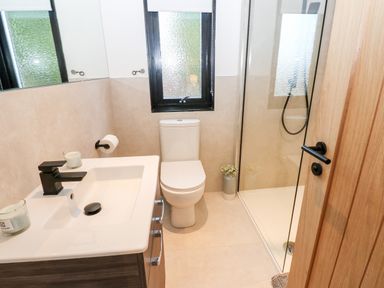 A bathroom with a sink, toilet, shower area, and window at Slaley Park Villa in Hexham