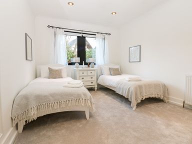 A bedroom with two single beds a nightstand with lamps and a window at Slaley Park Villa in Hexham