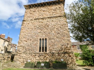 A stone building with a tall narrow window and flower planters in front at Slaley Park Villa in Hexham