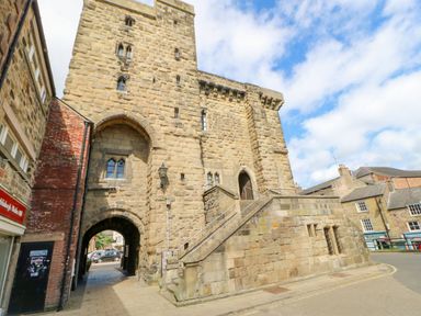 A stone castle gate with archways and stairs in a town setting at Slaley Park Villa in Hexham