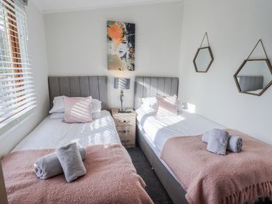 A bedroom with two beds and a bedside table at JacMar Lodge, 14 Applethwaite, Limefitt Park near Windermere