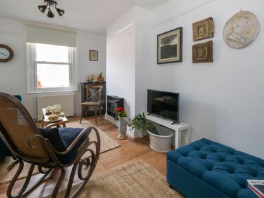 A living room with a rocking chair and a blue tufted ottoman at 26 High West in Weymouth