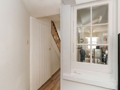 A hallway with white wooden doors and a window looking into a living area at 26 High West in Weymouth