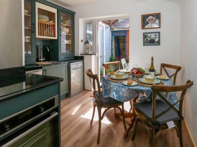 A kitchen with green cabinets a dining table set for four and a door opening to a small outdoor area at 26 High West in Weymouth
