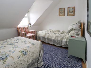 A bedroom with two single beds a striped armchair and a bedside table at 26 High West in Weymouth
