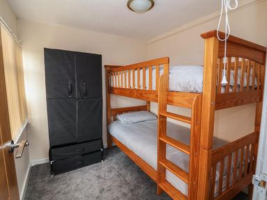 A small bedroom with wooden bunk beds and a black fabric wardrobe at Swiss Cottage in Wilsthorpe near Bridlington