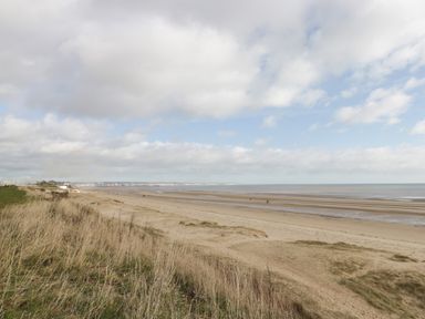 A sandy beach with grassy dunes and a cloudy sky at Swiss Cottage in Wilsthorpe near Bridlington