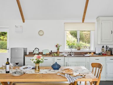 A kitchen with wooden table set with bread and flowers a window and appliances at The Farm Office in Bampton Devon