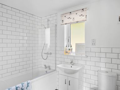 A bathroom with a bathtub shower combination sink cabinet toilet and window at The Farm Office in Bampton Devon