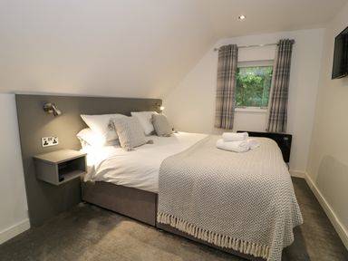 A bedroom with a double bed pillows bedside shelves and a window with curtains at Classic Lodge 30 in Dyserth