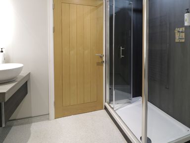 A bathroom with a wooden door a white sink on a countertop and a glass shower enclosure at Classic Lodge 30 in Dyserth