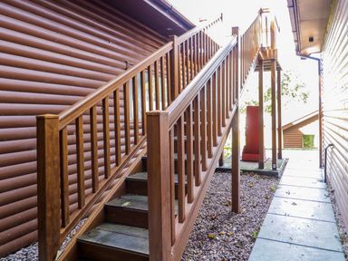 An outdoor wooden staircase between two log cabin style buildings at Classic Lodge 30 in Dyserth