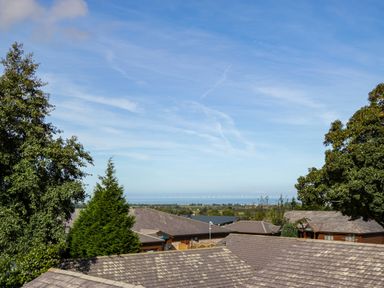 A view of rooftops trees and the sea under a blue sky at Classic Lodge 30 in Dyserth