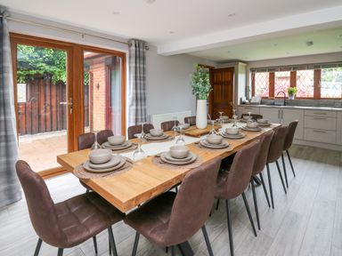 A dining area with a wooden table set for ten beside a kitchen at Pondarosa in Newbridge-On-Wye