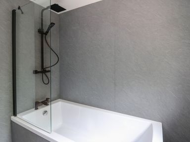 A bathroom with a white bathtub and a black shower fixture with a glass screen at Pondarosa in Newbridge-On-Wye