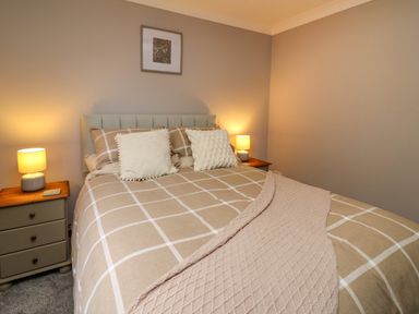 A bedroom with a double bed two side tables with lamps and a framed picture on the wall at Pondarosa in Newbridge-On-Wye